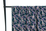 Fast viscose med hvide pumaer, der sidder på grene med lilla blade og lilla og hvide blomster vist draperet over stang og fra afstand