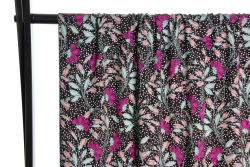 Fast viscose med små hvide prikker og blomster i lilla og blå toner på sort baggrund fra Atelier Jupe draperet over stang