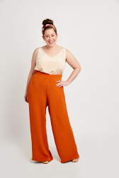 Kvinde smiler og poserer i stilfuldt outfit med bredbenede bukser.