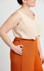 Kvinde i beige top og orange nederdel smiler.