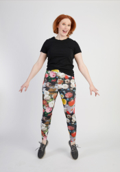 Kvinde med rødt hår i blomstrede leggings og sort t-shirt poserer muntert.