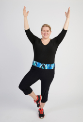 Kvinde laver yoga eller fitnessøvelse med løftede arme og et smil.