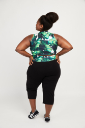 Kvinde poserer stolt, set bagfra, iført capri leggings og mønstret top.