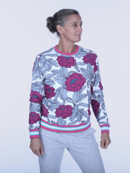 Kvinde i farverig trøje med blomsterprint poserer med et mildt smil.