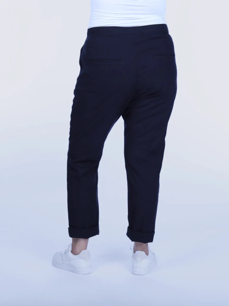 Person iført sorte bukser og hvide sneakers.