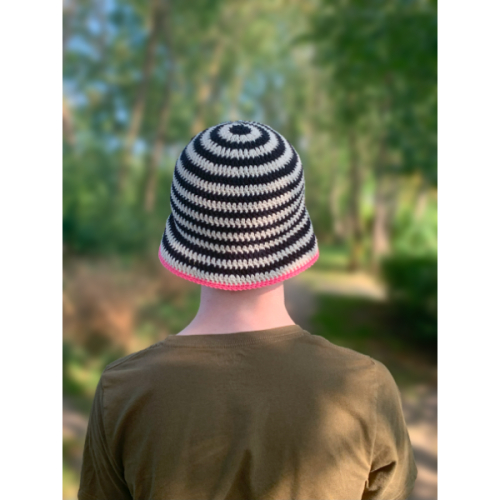 En hæklet bøllehat med sorte og hvide striber og pink kant på hovedet af en mand set bagfra.