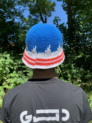 En hæklet bøllehat til FCK-fans set bagfra. Den er blå foroven med hvide takker op i det blå felt. Skyggen er hvid med to røde striber, der danner det danske flag.